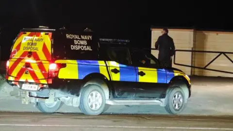 Eddie Mitchell A Royal Navy bomb disposal vehicle parked at a beach at night