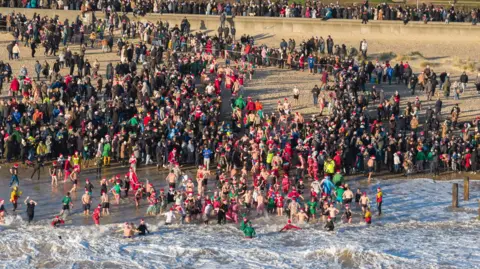 Oliv3r Drone Photography Swimmers enter the North Sea in Lowestoft, watched by crowds of people 
