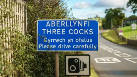 Getty Images A road sign as you enter Three Cocks village warning people to drive carefully in English and Welsh.