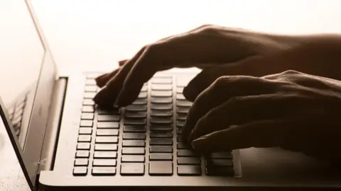 Hands typing on a laptop keyboard.