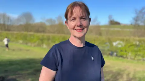 Woman in navy t shirt and short brown hair infront of hills