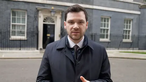 Henry Zeffman in suit, stood outside 10 Downing Street
