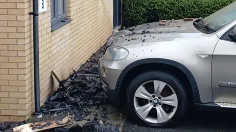Shane Proctor A silver parked car with debris from the fire across it's bonnet and on the floor in front of it.