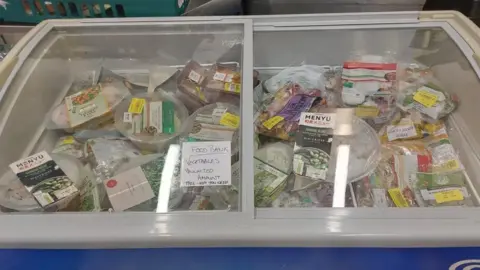 A glass-topped chest freezer full of packs of food