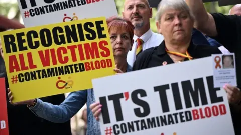 Getty Images Protestors hold placards with message related to the NHS infected blood scandal as Prime Minister Rishi Sunak gives evidence to the Infected Blood Inquiry in London, on 26 July, 2023