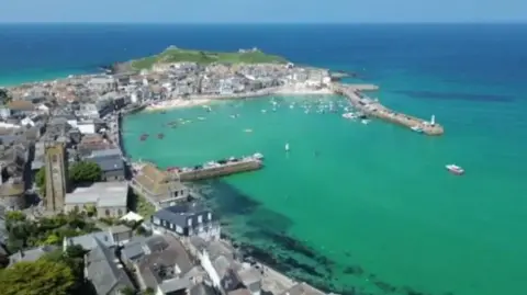 A seaside town is seen with beaches and homes surrounded by clear blue seas 