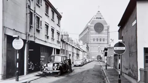 Regency Society A black and white image of a church and a road, with a car parked on the side of the street.