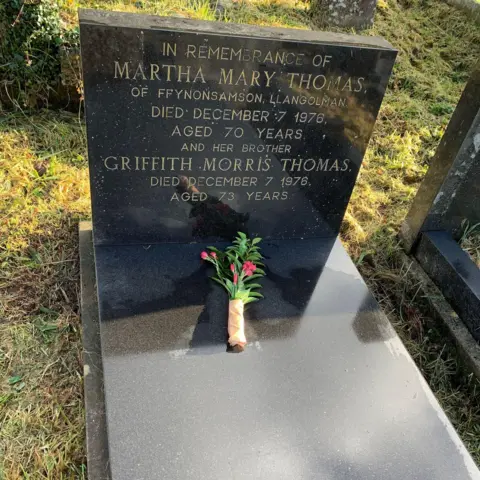The siblings' grave, with a bunch of flowers placed on top.