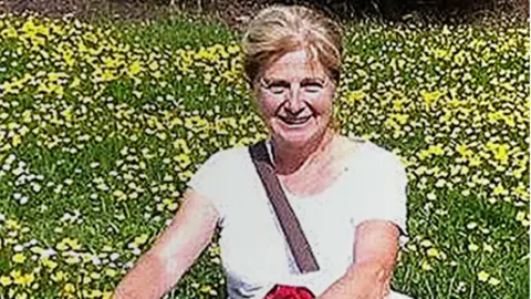 Wiltshire Police Danielle Carr-Gomm wearing a white t-shirt, standing in front of a flowery meadow