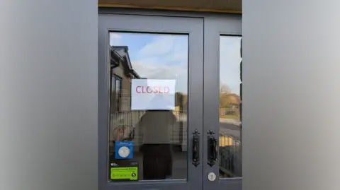 Nikita Stewart A white sign with red lettering saying 'closed' on a glass door.