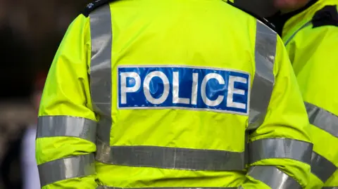 Stock image showing the back of a police officer wearing a high vis jacket 