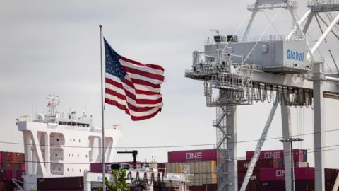 Getty Images The American flag flies over cargo containers at the Port Liberty on August 07, 2025 in Bayonne, New Jersey. 