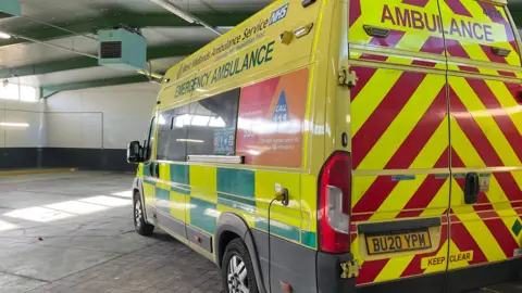 A West Midlands ambulance stands ready to be deployed from a station.