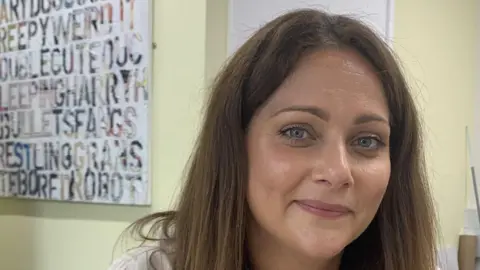 Michelle Graffagnino is one of the people responsible for the new micro-qualification. She has long brown hair and is smiling at the camera in front of a yellow wall.