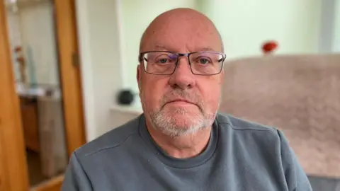 Man wearing glasses and grey jumper