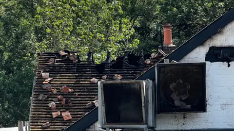 A close up of the damaged roof of the Crooked Billet Stoke Row following the fire. Tiles are scattered and appliances are burned.