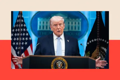 Getty Images Donald Trump wearing a dark blue suit and a light blue tie standing behind a podium