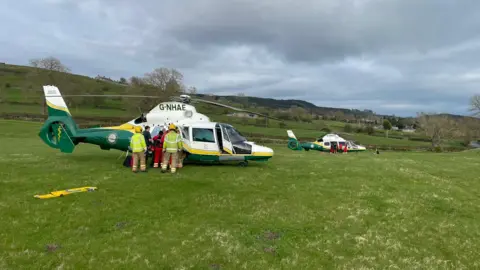 GNAAS Two helicopters in a field with paramedics loading the teenagers on