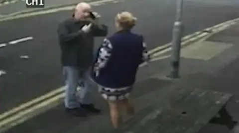 CPS Stephanie Langley and Matthew Bryant on a pavement facing each other, he is on the phone