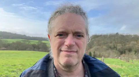 Councillor Matt McCabe standing in a field, staring into the camera. He is wearing a blue and black jacket.