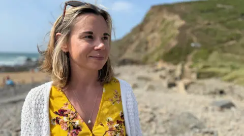 Head shot of Angharad stood at the beach looking out of frame