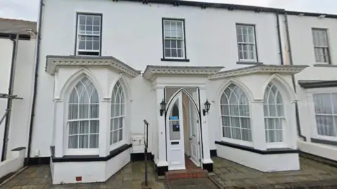 Former Guest House at 19 The Green, Seaton Carew. The white building has gothic shaped windows and sash windows one the second floor. 