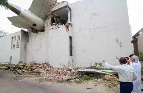 EPA-EFE/Shutterstock Narendra Modi looking up at the plane's tail that is crashed into a building.