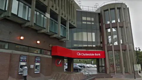 Historic Environment Scotland The rear view of the building showing the branding of the bank formerly known as Clydesdale Bank. A women can be seen using the ATM.