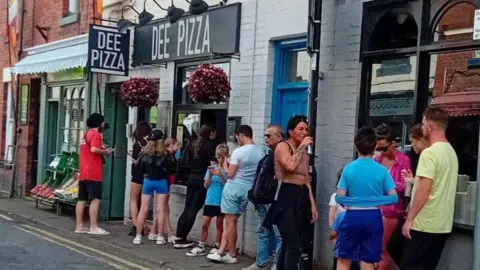 Dee Pizza People queue outside Dee Pizza in Llangollen.