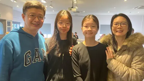 Tracy's two daughters stand between her and her partner for a family photo at the venue. Tracy's hands are on the shoulders of her younger daughter.