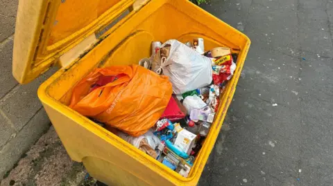 A grit bin full of rubbish.