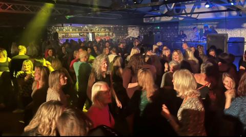 A crowded dance floor with people disco dancing 