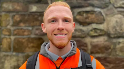 Lewis Freeman wearing hi-vis uniform with an orange jumper underneath