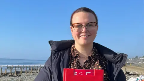Labour candidate Joanna Stallard standing smiling on a beach