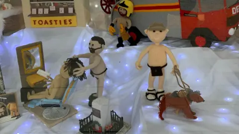 Nude knitted dog walker and nude knitted barber and person getting haircut with a nude knitted firefighter in the background.