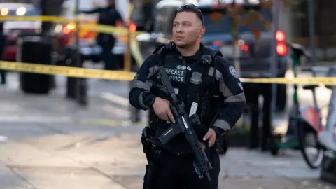A member of the US Secret Service stands guard while holding a gun in a cordoned-off area near the White House in Washington, DC on Wednesday.