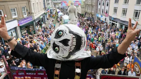 A person with a giant white ball on their head, with eyes and skeletal features drawn on it