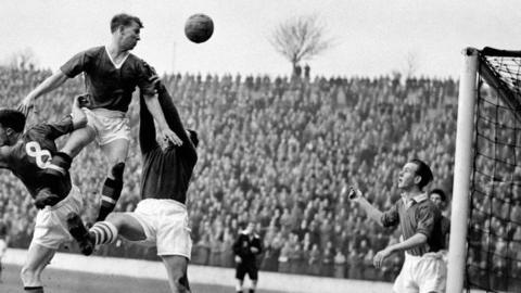 Bobby Charlton heads the ball towards Trevor Edwards (right) during a match between Charlton Athletic and Manchester United in 1957