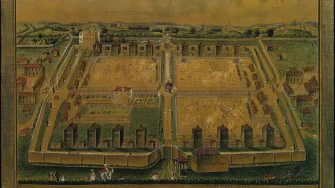 Peterborough Museum & Art Gallery Ancient drawing of Norman Cross prisoner of war camp shows a large fenced-off square area divided into four squares. There are watch towers on the north and south edges of the square with people visible in three of the smaller squares, with the remaining smaller square green coloured with what look like gardens.