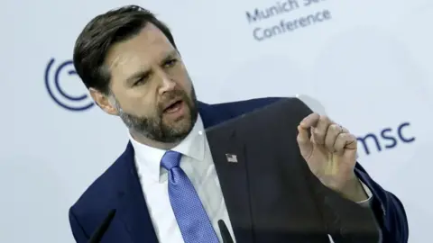 US vice president jd vance gives a speech wearing a blue suit and blue tie.