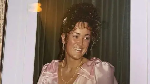 Family photo Carol in old family photo in pink satin dress and pearl necklace. She is laughing and looking sideways and has brown curly hair worn up and long earrings