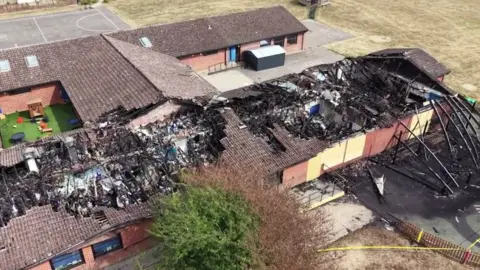 BBC An aerial image of a fire-wrecked single storey building. The roof has been destroyed in parts and the inside of the building blackened by fire and smoke.