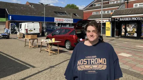 Shariqua Ahmed/BBC Vicky Hammond stands in a market square and looks at the camera