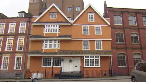 An exterior view of the Partou Nursery building on King Street. It is an orange building with four floors. It has white windows and white doors with a few steps up to them.
