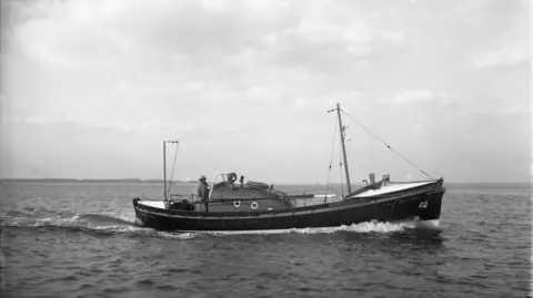 RNLI A black and white photo of an old lifeboat at sea.