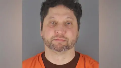 Minneapolis PD/Hennepin County Sheriff Processing image of Kazmierczak, looking into the camera and wearing an orange shirt