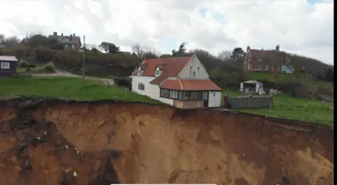 A drone image of the farmhouse partially hanging over the cliff edge