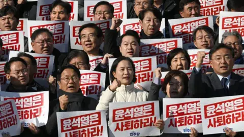 Getty Images Lawmakers stand in four rows holding red ad white placards reading "Yoon Suk Yeol should resign!" during a rally against President Yoon Suk Yeol at the National Assembly in Seoul on December 4, 2024, after martial law was lifted in South Korea.