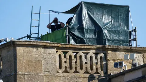 PA Media  A security officer peering at a photographer through binoculars on the roof of Blenheim Palace 