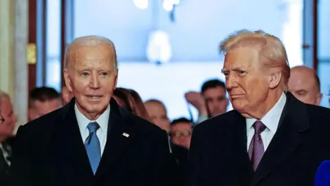 Joe Biden (left) in a black suit and blue tie and Donald Trump in a suit and purple tie at the Capitol Rotunda in DC for Trump's inauguration ceremony, where he will be sworn in as the 47th US president